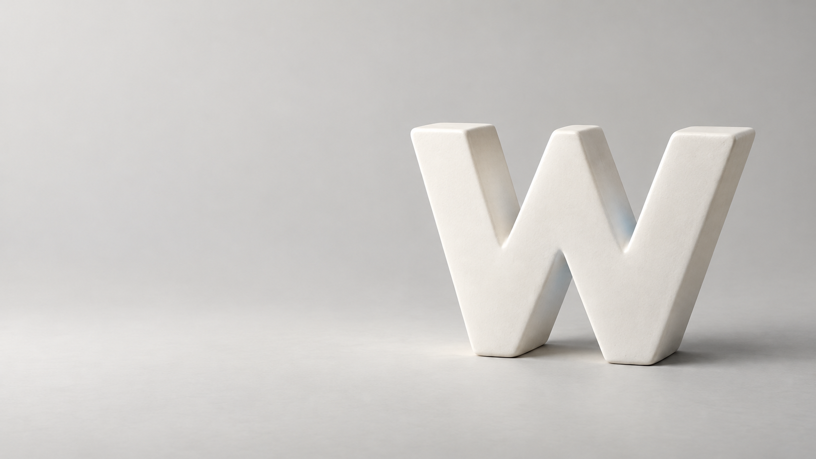 Matte ivory ceramic W sculpture with softly rounded edges